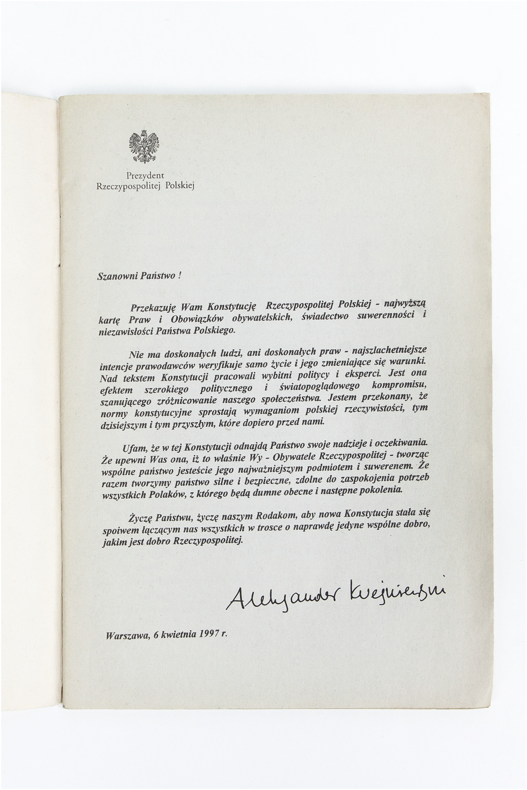 Zdjęcie przestawia pierwszą stronę Konstytucji RP. Na górze godło Polski, czarna pieczęć orła w koronie. Poniżej napis: Prezydent Rzeczypospolitej Polskiej. Poniżej treść wstępu do konstytucji podpisana przez Prezydenta Aleksandra Kwaśniewskiego. Na dole strony miejsce i data: Warszawa, 6 kwietnia 1997 roku.