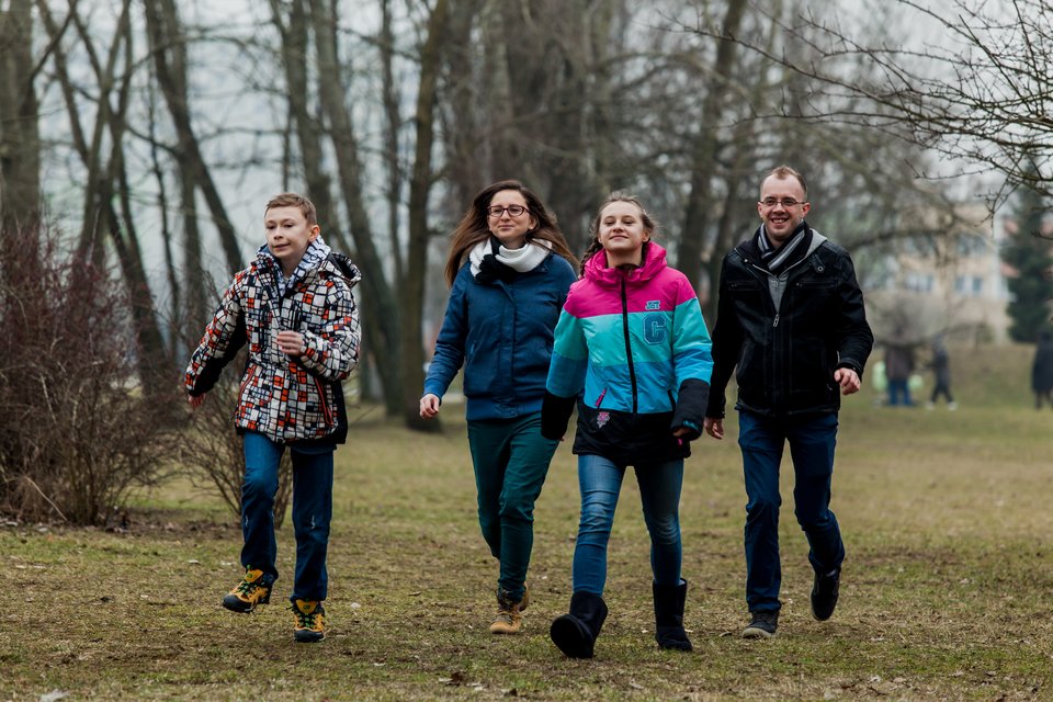 Fotografia przedstawia cztery osoby biegające lub spacerujące szybkim krokiem po jesiennym parku.