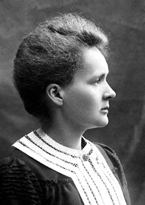 Zdjęcie przedstawia Marię Skłodowską-Curie, polską fizyczkę i chemiczkę pracującą we Francji, jedyną dwukrotną laureatkę nagrody Nobla, a zarazem jedynego uczonego w historii, który otrzymał tę nagrodę w dwóch różnych dziedzinach nauk przyrodniczych. Zdjęcie przedstawia ją z profilu podczas odbierania nagrody Nobla z fizyki w 1903 roku.
