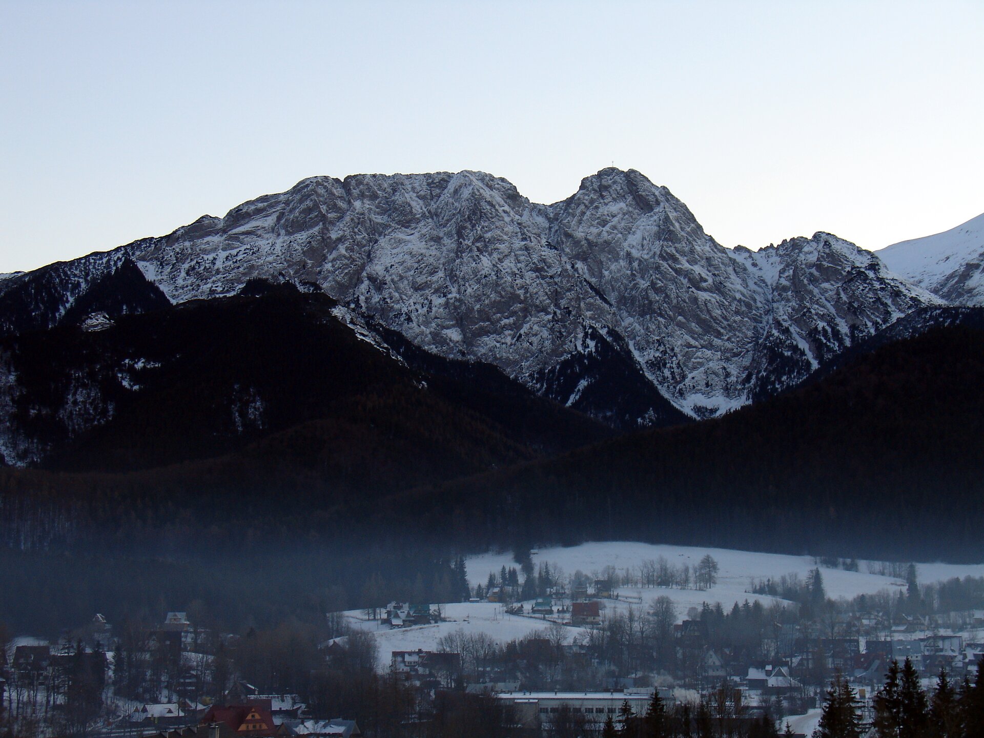 Fotografia prezentuje ośnieżony szczyt górski, Giewont, który swoim kształtem przypomina głowę śpiącego rycerza.
