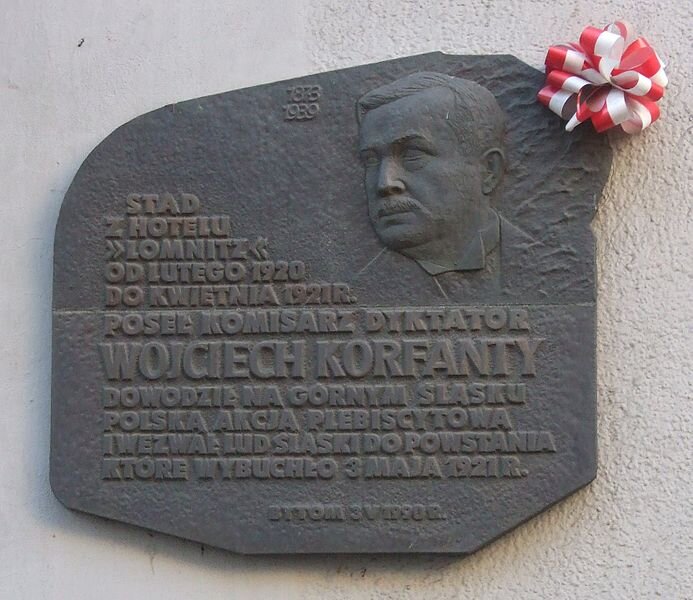 Tablica kamienna ku czci W. Korfantego o dość nieregularnym kształcie. Na niej podobizna Korfantego oraz napis: „1873. 1939. Stąd z hotelu „Lomnitz” od lutego 1920 do kwietnia 1921 r. poseł komisarz dyktator Wojciech Korfanty dowodził na Górnym Śląsku polską akcją plebiscytową i wezwał lud śląski do powstania, które wybuchło 3 maja 1921 r. Bytom, 3 V 1990 r Źródło: Yarl, Tablica kamienna ku czci W. Korfantego o dość nieregularnym kształcie. Na niej podobizna Korfantego oraz napis: „1873. 1939. Stąd z hotelu „Lomnitz” od lutego 1920 do kwietnia 1921 r. poseł komisarz dyktator Wojciech Korfanty dowodził na Górnym Śląsku polską akcją plebiscytową i wezwał lud śląski do powstania, które wybuchło 3 maja 1921 r. Bytom, 3 V 1990 r, licencja: CC BY-SA 2.5.
