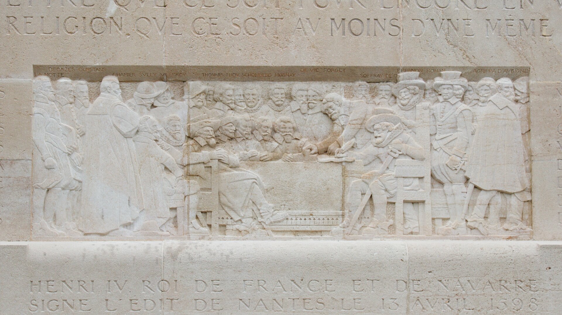 Relief na pomniku reformacji w Genewie przedstawiający podpisanie edyktu nantejskiego przez Henryka IV w 1598 r. Więcej o samym pomniku - por. informacje z lekcji 88. U dołu napis „HENRI IV ROI DE FRANCE ET DE NAVARRE SIGNE L’EDIT DE NANTES LE 13 AVRIL 1598” (Henryk IV król Francji i Nawarry podpisuje edykt Nantejski 13 kwietnia 1598). Relief na pomniku reformacji w Genewie przedstawiający podpisanie edyktu nantejskiego przez Henryka IV w 1598 r. Więcej o samym pomniku - por. informacje z lekcji 88. U dołu napis „HENRI IV ROI DE FRANCE ET DE NAVARRE SIGNE L’EDIT DE NANTES LE 13 AVRIL 1598” (Henryk IV król Francji i Nawarry podpisuje edykt Nantejski 13 kwietnia 1598). Źródło: Clément Bucco-Lechat, Wikimedia Commons, licencja: CC BY-SA 3.0.