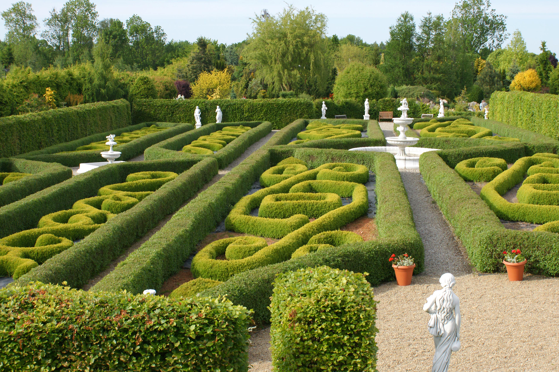Fotografia prezentuje ogród francuski ze starannie formowanymi wzorami z roślin.