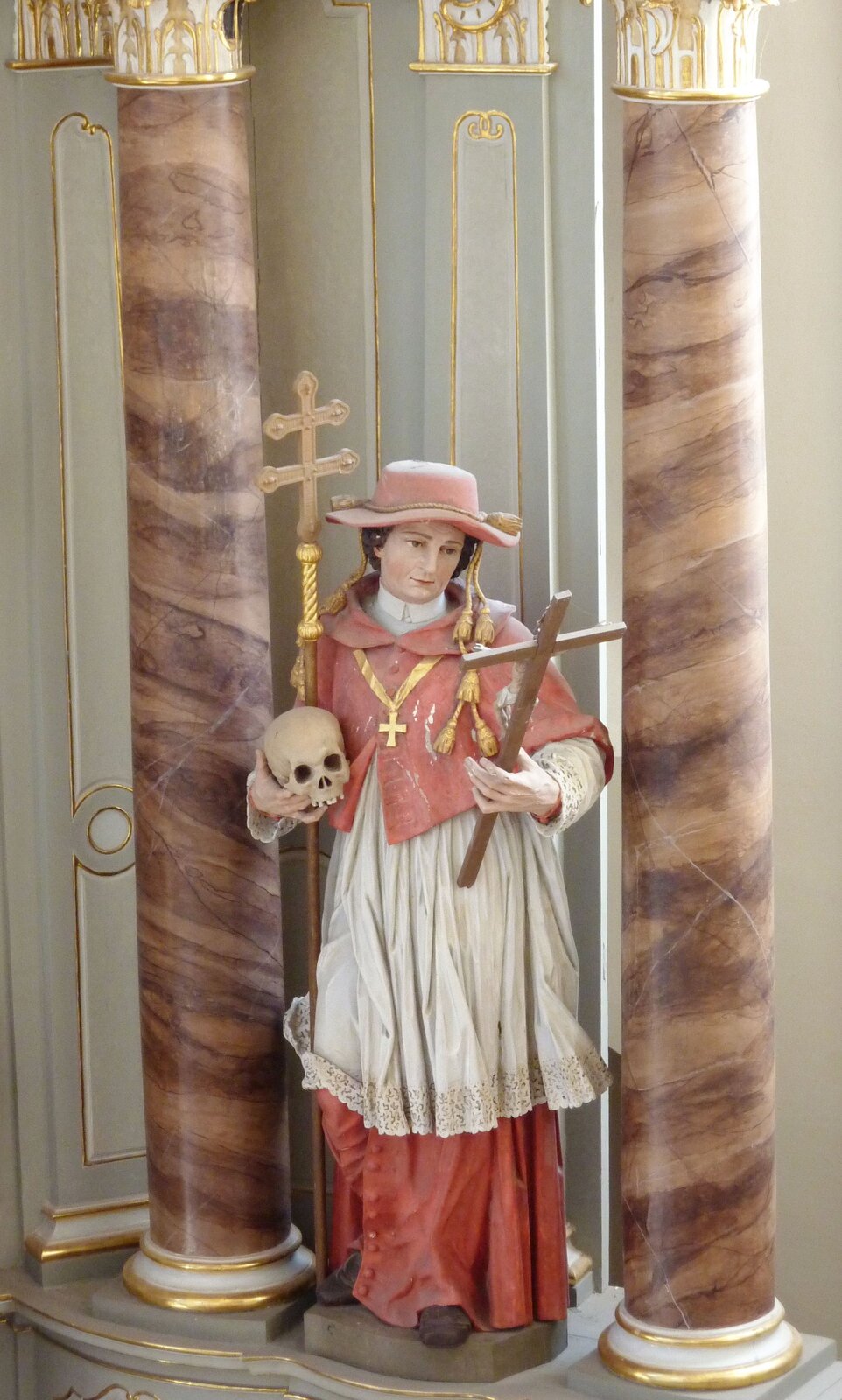Rzeźba św. Karola Boromeusza w stroju kardynalskim Figura z dawnego klasztoru cystersów w Wehlen w Nadrenii-Palatynacie. Święty pokazany został w stroju kardynalskim. Godność tę otrzymał od swojego wuja papieża Piusa IV. Źródło: GFreihalter, Rzeźba św. Karola Boromeusza w stroju kardynalskim, 2012, fotografia, licencja: CC BY-SA 3.0.