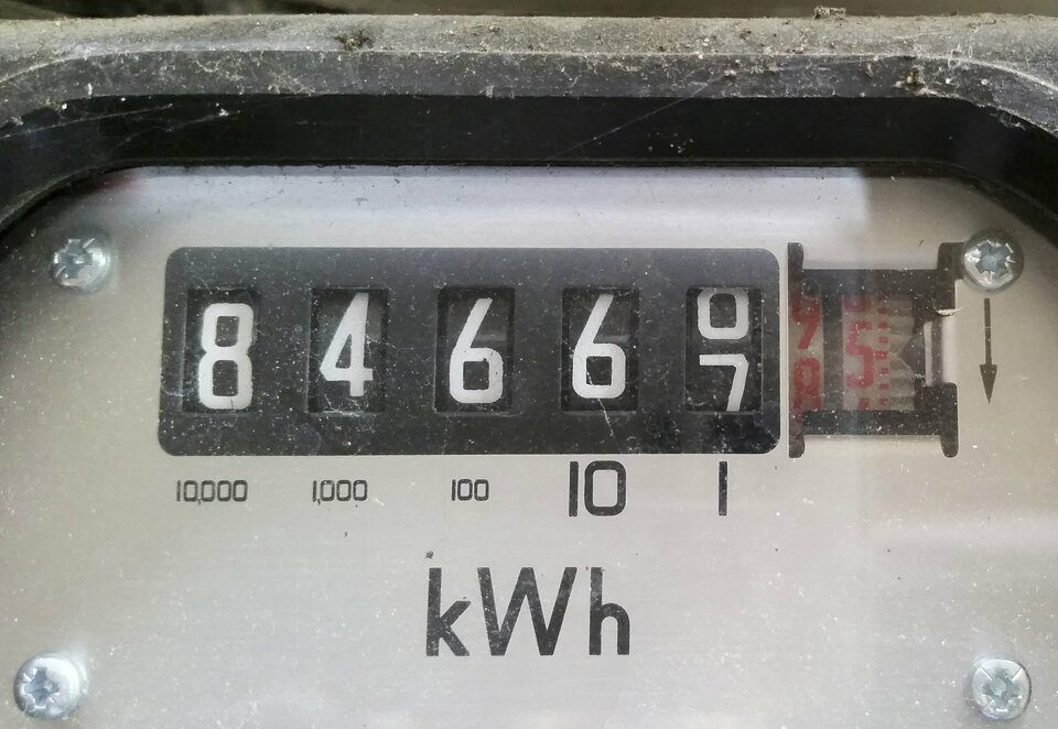 Zdjęcie przedstawia zbliżenie fragmentu przedniego panelu licznika energii elektrycznej, a dokładniej tarczę licznika wskazującą wartość 84667,5 oraz symbol jednostki kWh poniżej.