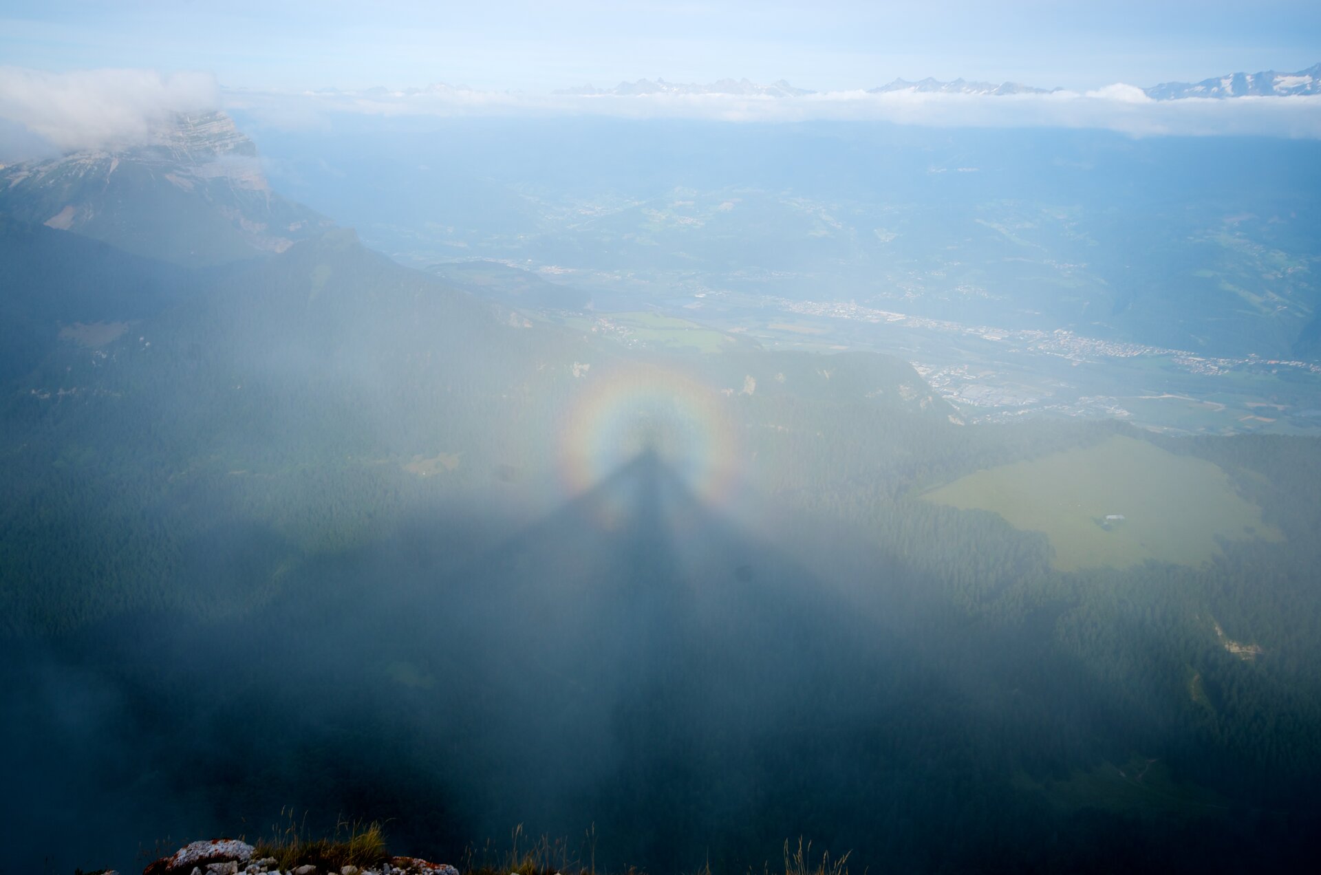Fotografia prezentuje zjawisko optyczne spotykane w górach, nazwane Widmem BrockenuNa fotografii widoczny cień osoby na chmurze, która znajduje się poniżej obserwatora. Cień otoczony jest tęczową obwódką zwaną glorią.