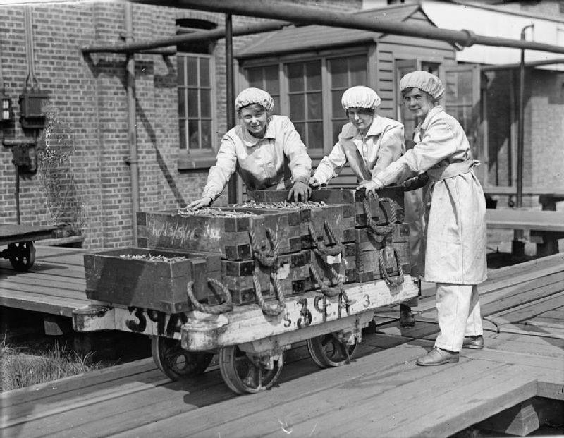 Kobiety pchające wagon z łuskami do amunicji Źródło: Lewis, Kobiety pchające wagon z łuskami do amunicji, 1918, Imperial War Museums, domena publiczna.
