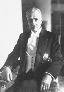Zdjęcie przedstawia Ignacego Mościckiego z okresu jego prezydentury w latach 1926 do 1939, siedzącego na krześle z rękami na oparciach bocznych i spoglądającego w przestrzeń po prawej stronie fotografa.