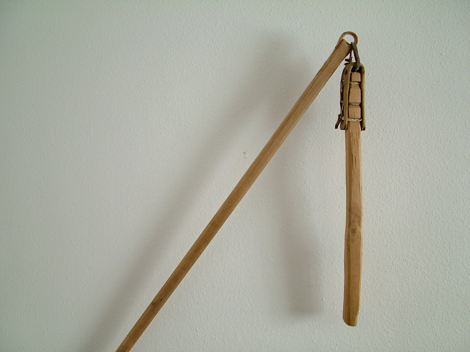 Na końcu długiej tyczki sznurkiem i rzemieniem przyczepiony jest krótszy drąg.