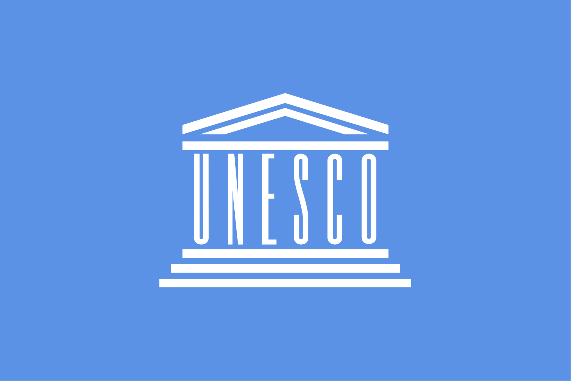 Ilustracja przedstawia białe logo organizacji UNESCO na błękitnym tle. Logo w kształcie budynku. Górna część to spadzisty trójkątny dach wsparty na białej poziomej linii. Poniżej pionowo ustawione litery UNESCO. Litery tworzą kolumny budynku. Poniżej liter trzy poziome białe linie. Każda linia poniżej jest nieco dłuższa od poprzedniej. Linie to schody prowadzące do budynku.