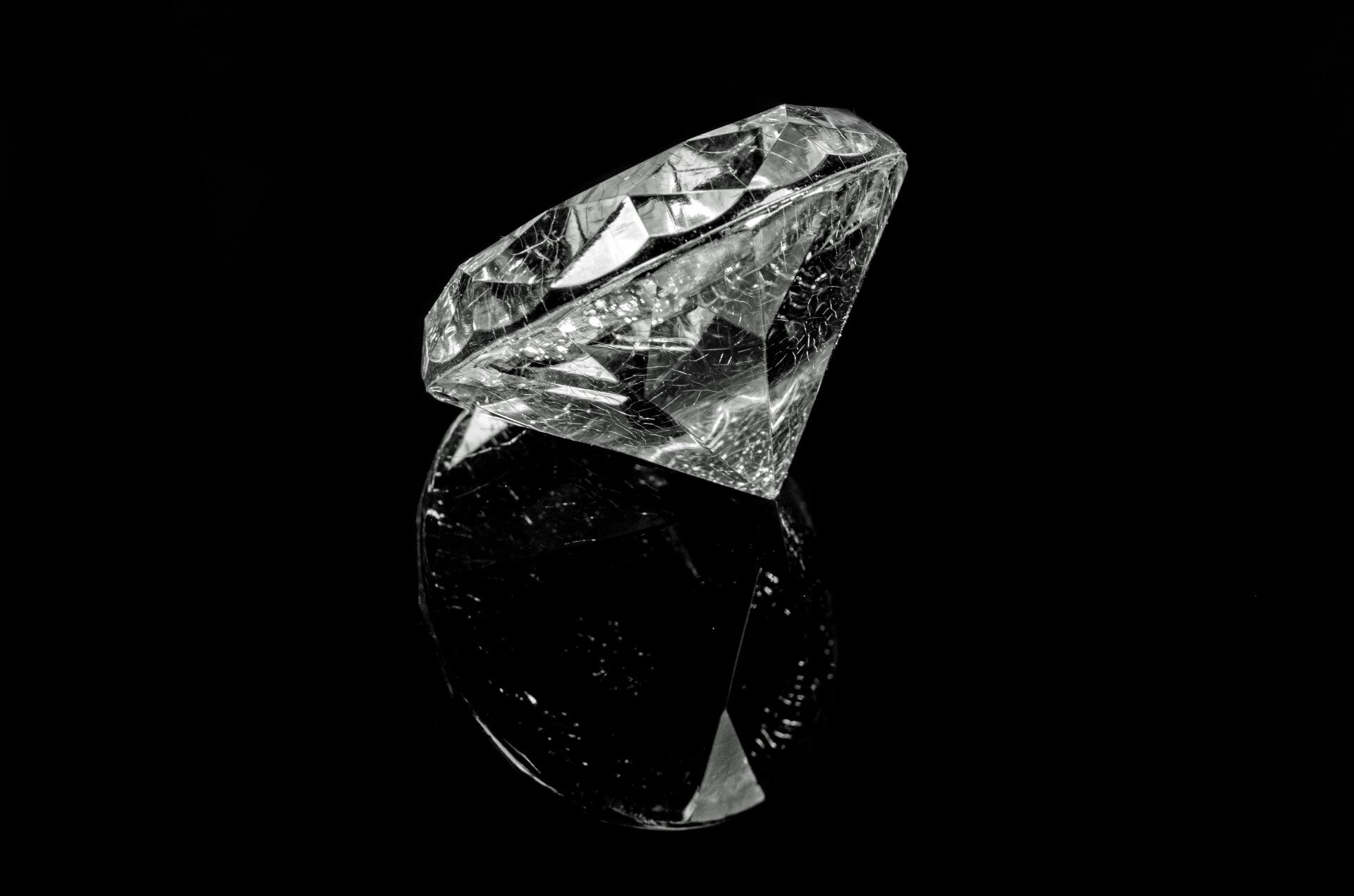 Na zdjęciu przezroczysty bezbarwny minerał. To oszlifowany diament. Kształtu stożkowego wycinka kuli, pozbawionego jego najbardziej wierzchniej części. Czarne tło.