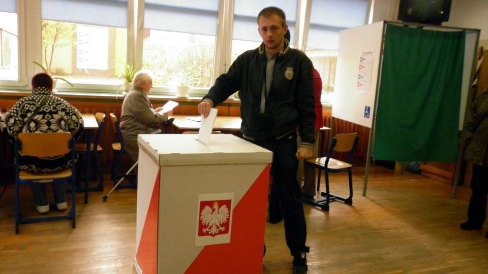 Wybory parlamentarne - mężczyzna przy urnie wyborczej