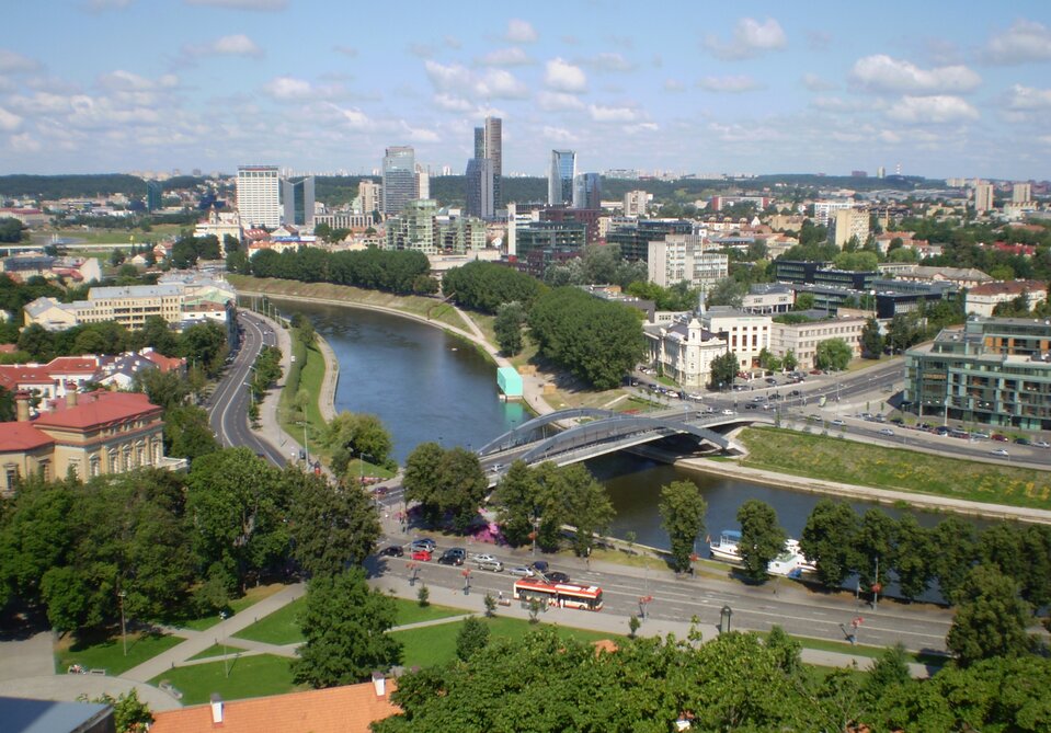 Na zdjęciu nowoczesna zabudowa miejska, wysokie budynki, rzeka, most, ulice.