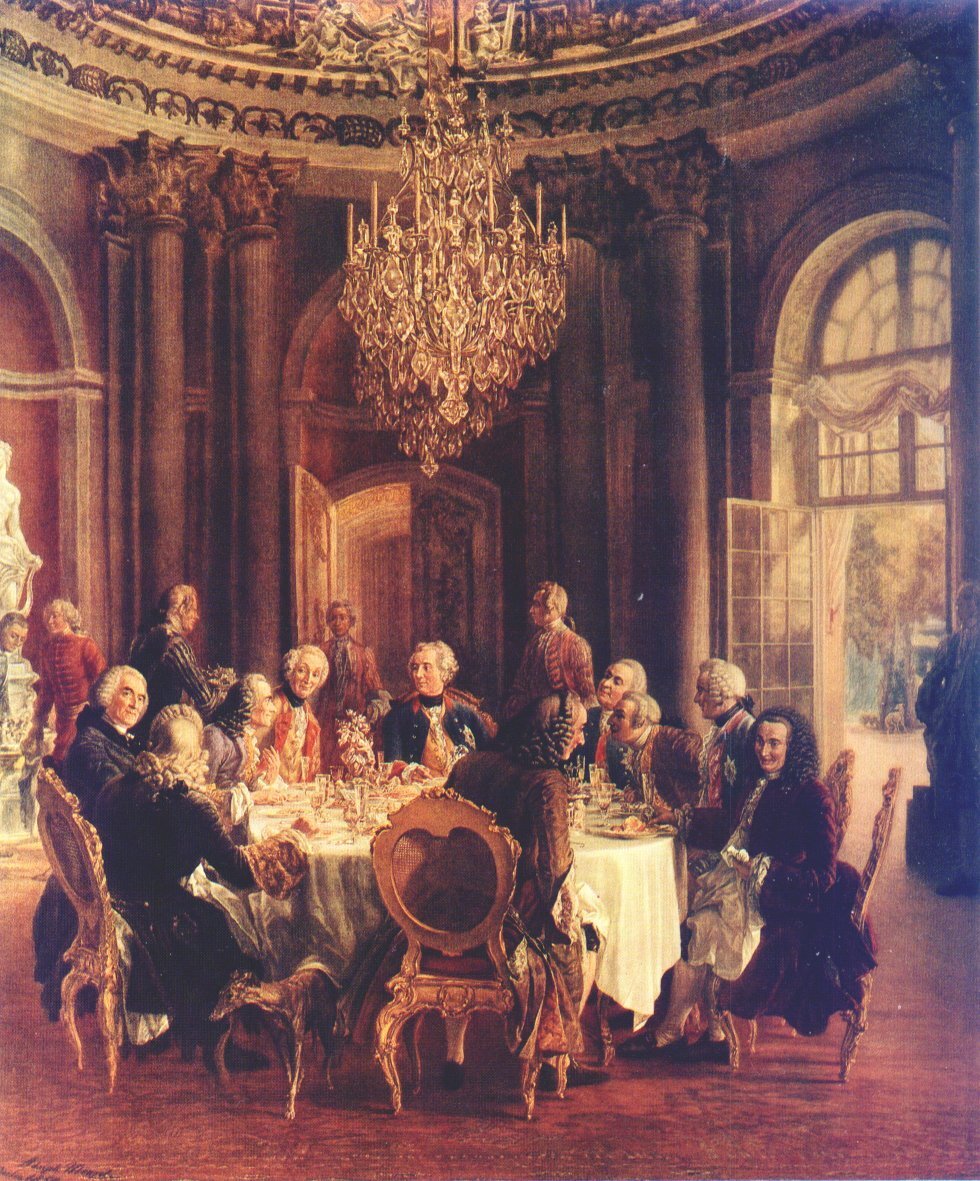 Okrągły stół u króla Fryderyka II Wśród namalowanych postaci znajduje się Wolter (siedzi po lewej stronie, patrzy „w stronę widza”). Źródło: Adolph von Menzel, Okrągły stół u króla Fryderyka II, 1850, olej na płótnie, domena publiczna.