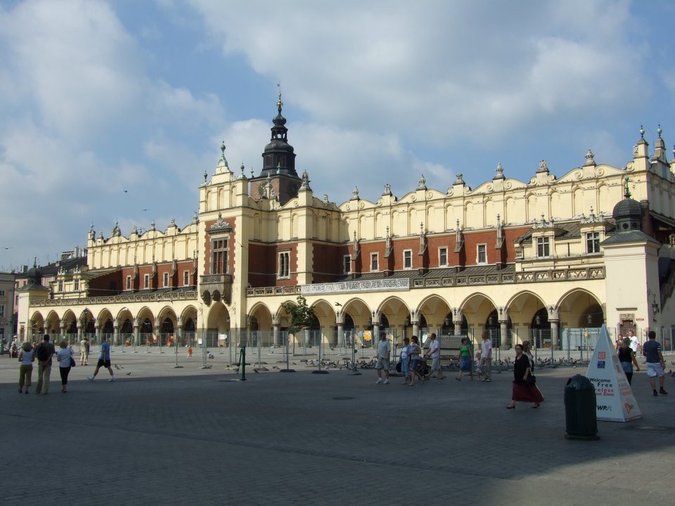 Sukiennice w Krakowie. Nowe, gotyckie sukiennice wystawił król Kazimierz Wielki przed 1358. Środkowa hala o długości 108 m i szerokości 10 m z dwóch stron miała dostawione dwa rzędy kramów. Budynek spłonął w 1555 r. i wówczas (1556-1559) rozpoczęto odbudowę. Zastosowano szereg elementów renesansowych – attykę, loggie. Przy pracach tych działali włoscy artyści Santi Gucci i Jan Maria Padovano. Sukiennice w Krakowie. Nowe, gotyckie sukiennice wystawił król Kazimierz Wielki przed 1358. Środkowa hala o długości 108 m i szerokości 10 m z dwóch stron miała dostawione dwa rzędy kramów. Budynek spłonął w 1555 r. i wówczas (1556-1559) rozpoczęto odbudowę. Zastosowano szereg elementów renesansowych – attykę, loggie. Przy pracach tych działali włoscy artyści Santi Gucci i Jan Maria Padovano. Źródło: Necrothesp, Wikimedia Commons, licencja: CC BY-SA 3.0.