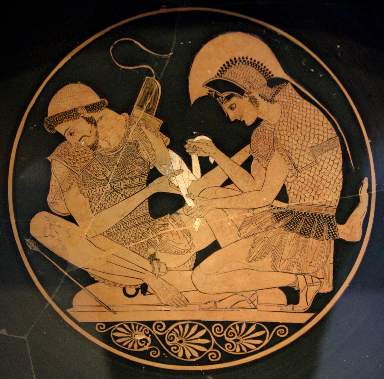Achilles opatrujący rannego Patroklosa Scena wykonana we wnętrzu czerwonofigurowej czary z Vulci Źródło: Sosias, Achilles opatrujący rannego Patroklosa, ok. 500 r. p.n.e., British Museum, Londyn, domena publiczna.